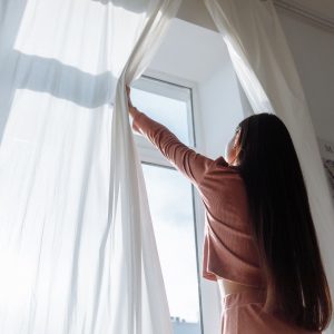 Kéo rèm đón nắng sớm bên cửa sổ buổi sáng