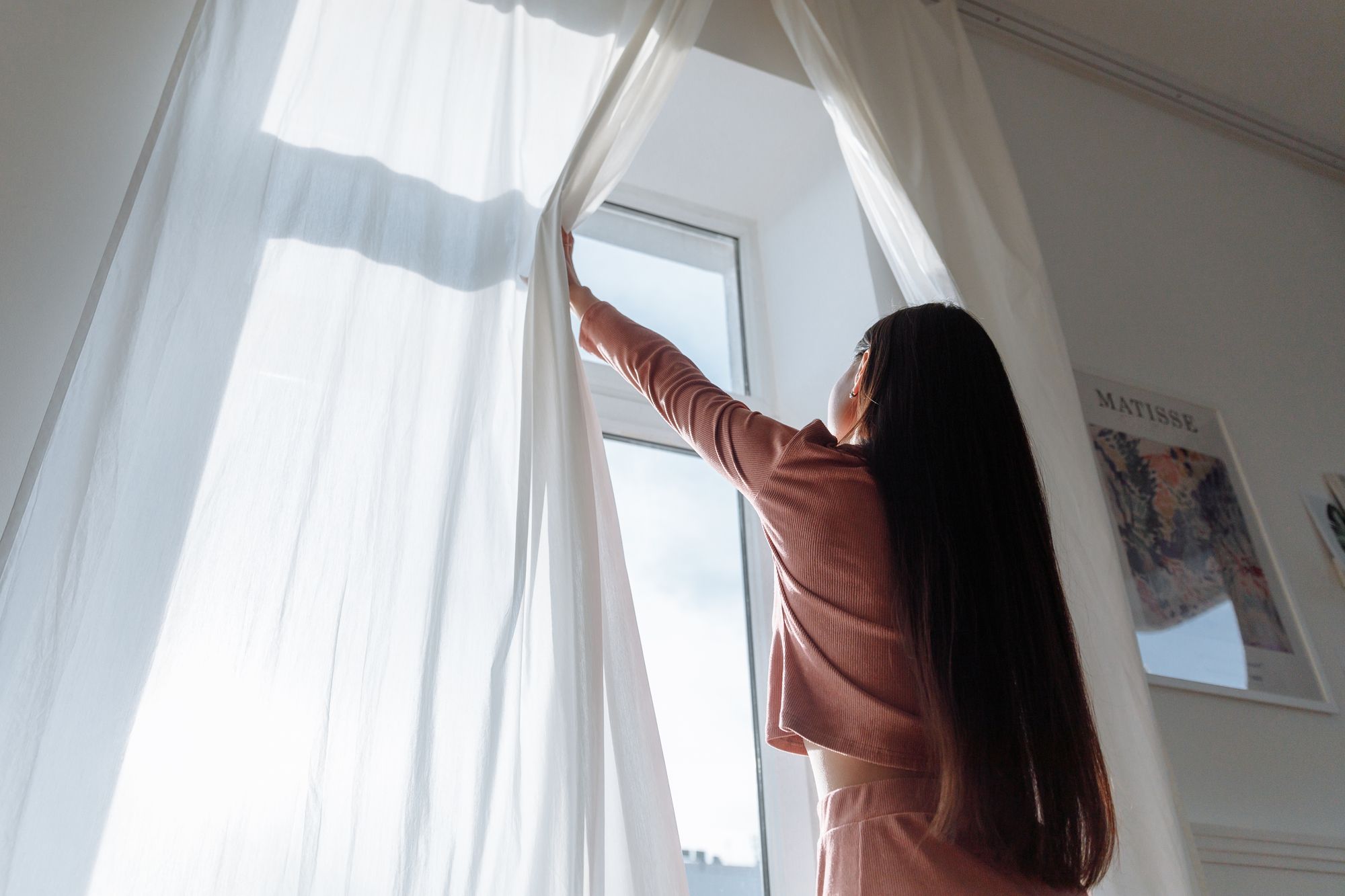 Kéo rèm đón nắng sớm bên cửa sổ buổi sáng